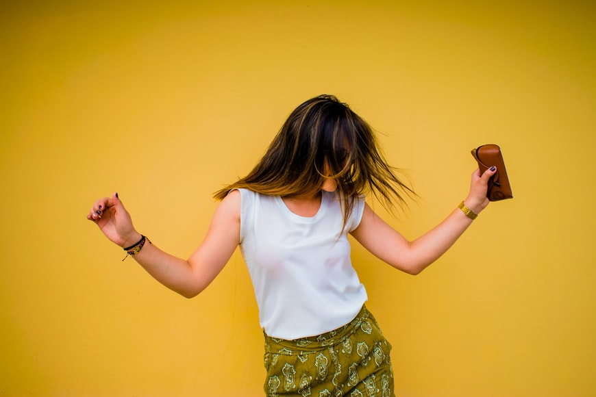 happy woman standing near yellow wall