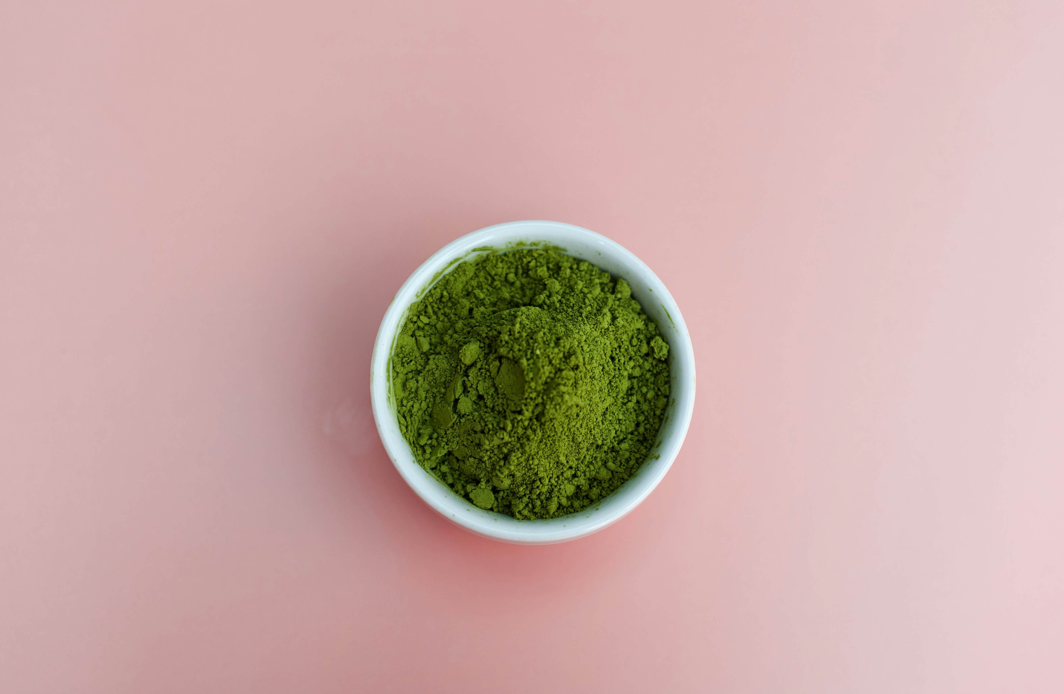 Green kratom powder in a white bowl